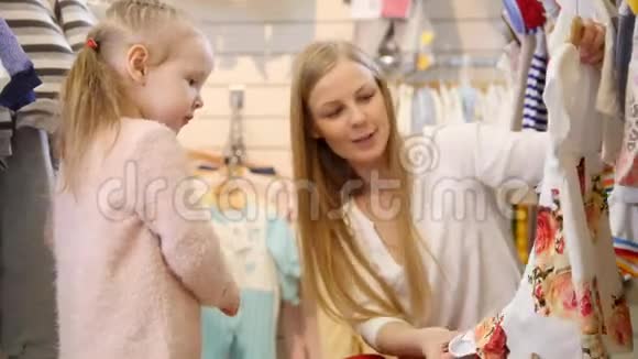 妈妈带着金发女儿在商店买儿童服装视频的预览图