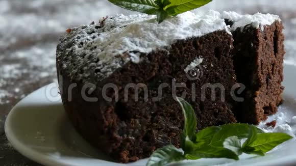 自制的烤巧克力巧克力蛋糕在一个用薄荷叶装饰的白色盘子上裹着糖粉叉叉视频的预览图