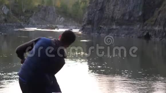 年轻人缓慢地向山河投掷石块3840x2160视频的预览图