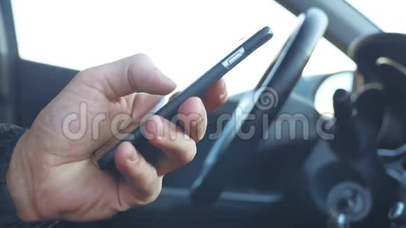 男人在车里拿着智能手机男人在智能手机上获得短信在线社交媒体生活方式交流视频的预览图
