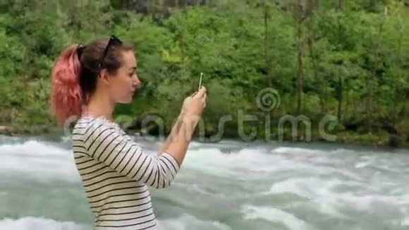 女孩用智能手机在河边拍照视频的预览图