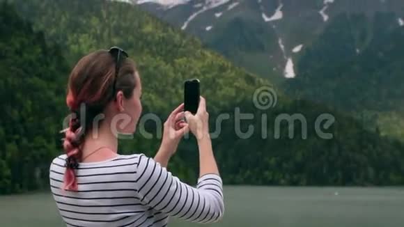 在湖边用智能手机拍照的女孩视频的预览图