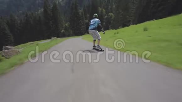 年轻的职业滑板运动员在美丽的森林景观中沿着空旷的乡间小路沿着长板下坡视频的预览图