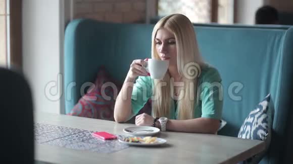 金发女郎喝着咖啡看着她的手表视频的预览图