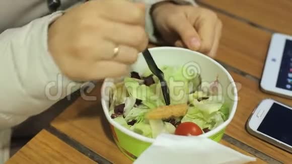 一位中年白人妇女在一个寒冷的夜晚坐在一家夏季咖啡馆的桌子旁吃蔬菜沙拉和油炸食品视频的预览图
