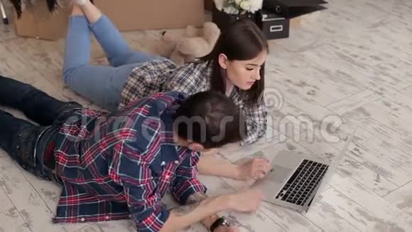 新房子里有台手提电脑的年轻夫妇视频的预览图