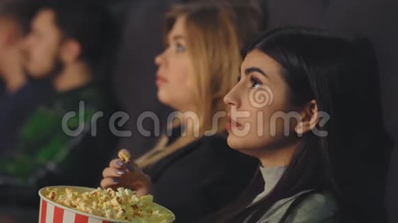 一个在电影院吃爆米花看电影的漂亮女孩视频的预览图