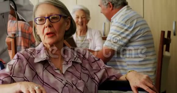 女医生跪在轮椅上与残疾老年妇女交谈视频的预览图
