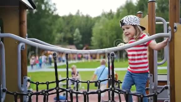 一个可爱的小女孩在公园操场成功地穿过网桥视频的预览图