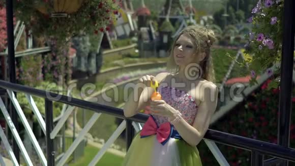 年轻的金发女人在花园里吹肥皂泡漂亮的梦想可爱的女孩穿着滑稽的蕾丝礼服放松视频的预览图