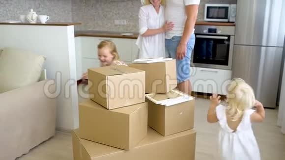 年轻幸福的家庭搬到新公寓两个小女孩和父母一起跑进新家的背景纸板视频的预览图