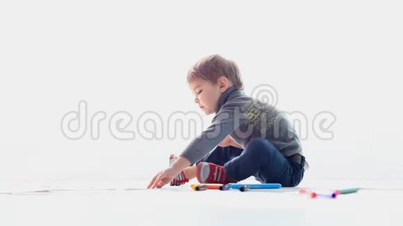 一个男孩坐在白色的地板上画画视频的预览图