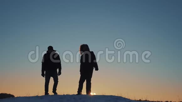 两个徒步旅行的游客走在日落山顶剪影团队合作旅游业务理念两个人视频的预览图