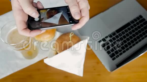 有智能手机的人用笔记本电脑拍摄汉堡快餐食品顶部视图视频的预览图