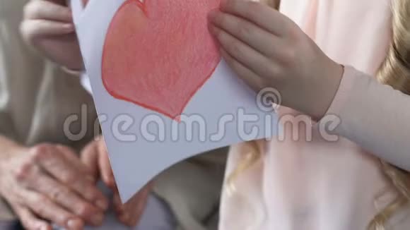 女孩带着爱心亲情关怀向奶奶展示手工贺卡视频的预览图