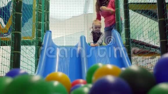 一个可爱的孩子在游乐园里从蓝色过山车上拉下来多彩球遇到男孩视频的预览图