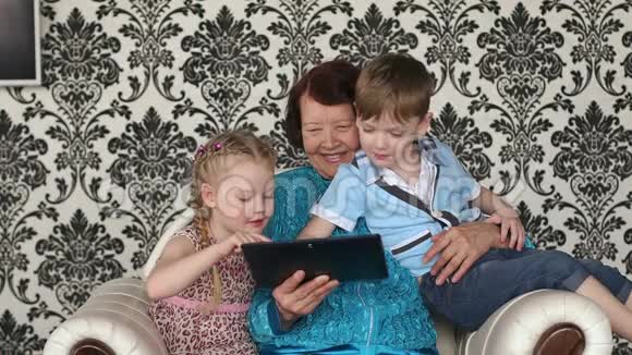 祖母和孙子孙女们坐在沙发上视频的预览图