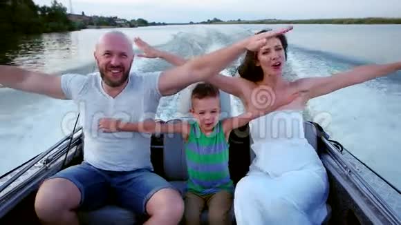 父母带着一个孩子在河上避暑幸福的家庭在船上爸爸妈妈和儿子一起度过时光视频的预览图