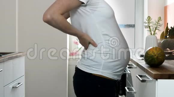 一个穿着白色t恤和黑色裤子的孕妇揉着肚子的躯干视频的预览图