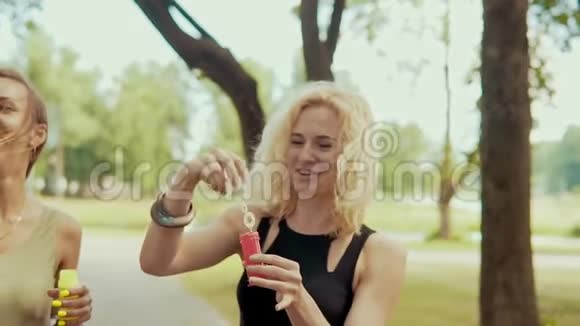 带着太阳镜的快乐女孩在公园玩泡泡视频的预览图