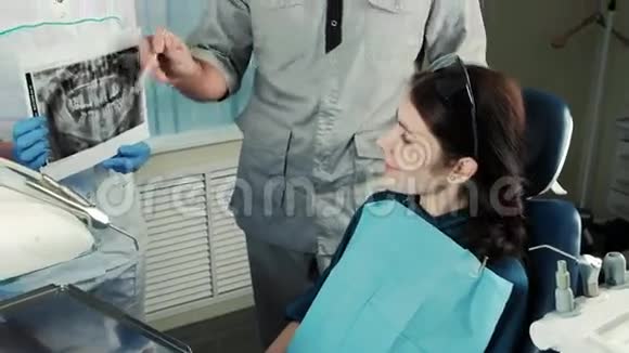 牙医与他的病人讨论x光哪个护士持有视频的预览图
