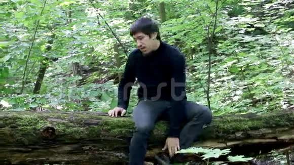 人坐在木头上的一棵倒下的树上伸手去拿蘑菇一个人在树林里醒来视频的预览图