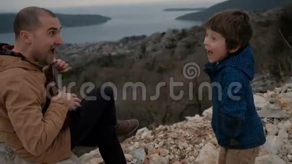 微笑的男人带着吉他男孩在悬崖边视频的预览图