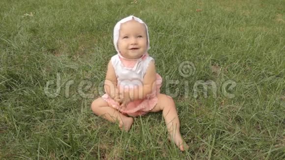 一个小女孩坐在草地上拍手微笑夏天视频的预览图
