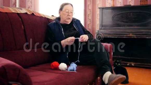 老年妇女养老金领取者家庭针织羊毛袜子坐在沙发上老年妇女的爱好视频的预览图