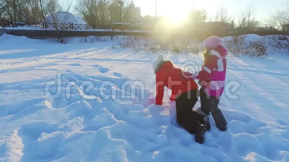 在雪地上快乐的冬天妈妈和女儿在阳光明媚的冬季公园玩耍视频的预览图