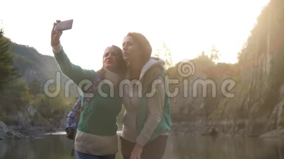 年轻女性正在电话里自拍背景是大山和青山河视频的预览图