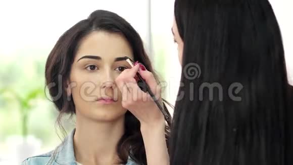 在美容院设计眉毛女孩眼影用刷子涂眉毛眉笔画轮廓视频的预览图