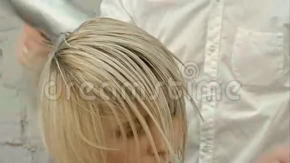 理发师用吹风机烘干女士的头发视频的预览图
