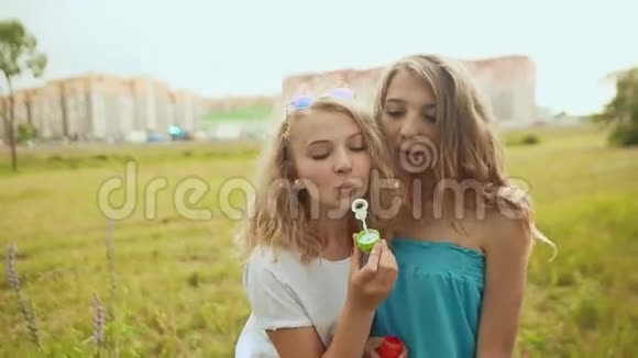 两个女孩在城市背景下吹肥皂泡视频的预览图