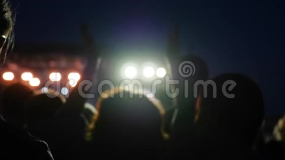 女人在摇滚节上双手跳跃舞台上灯火辉煌夜间摇滚音乐会上灯火辉煌视频的预览图