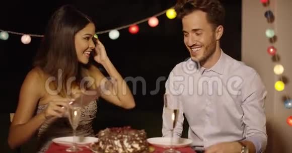 年轻的一对受欢迎的夫妇一边切蛋糕一边开玩笑视频的预览图