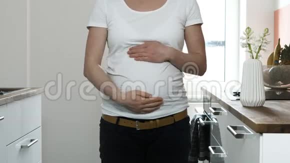 穿白色T恤衫黑色裤子和苹果的孕妇躯干视频的预览图