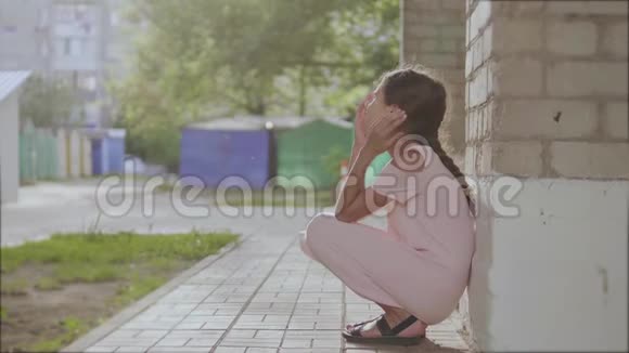 悲伤的小女孩坐在砖头旁边的墙上沮丧的慢动作视频少女伤心视频的预览图