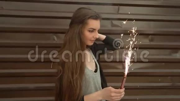 特写镜头一个女人手里拿着火花在棕色墙壁前的街道上动作缓慢视频的预览图
