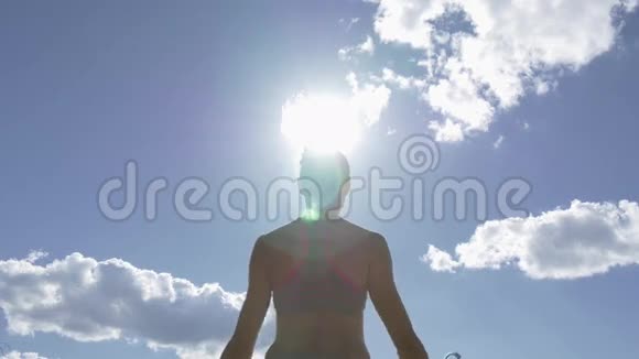 高加索女人在海滨练习瑜伽以蓝天为背景太阳在框架中闪耀视频的预览图