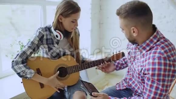 年轻快乐有爱心的一对夫妇学习用平板电脑弹声吉他坐在那里玩得开心视频的预览图