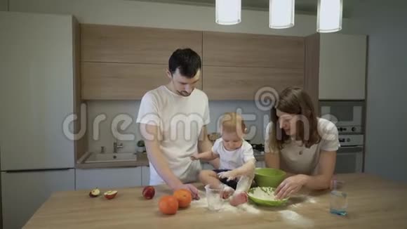 父母和一个小女儿一起在家里的厨房做饭家庭的概念视频的预览图