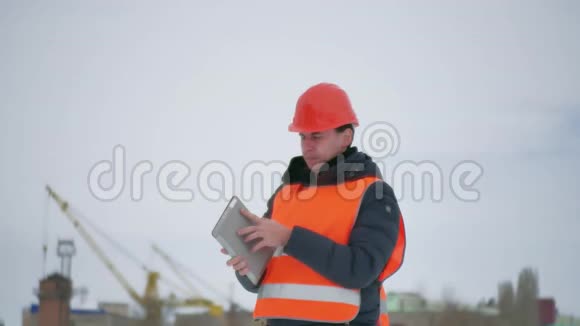 建筑设计师戴着头盔在施工现场用平板电脑建筑业工人冬季建筑视频的预览图