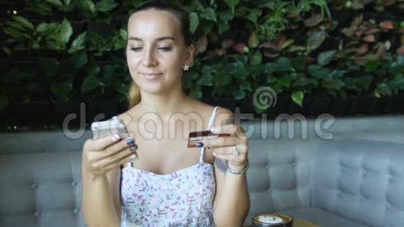 有纹身的女人在网上购物在咖啡馆里用信用卡和手机视频的预览图
