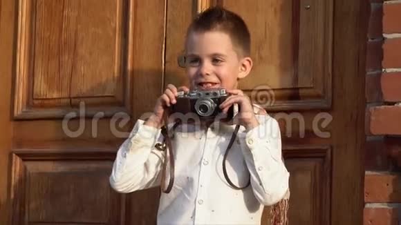 小男孩在复古相机上拍照在砖楼背景下穿着复古的衣服视频的预览图