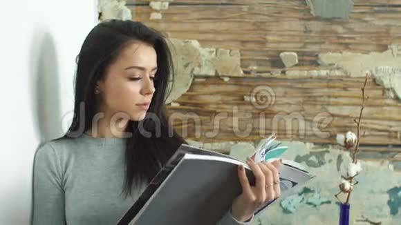 一个漂亮的女孩在看一本光滑的杂志视频的预览图