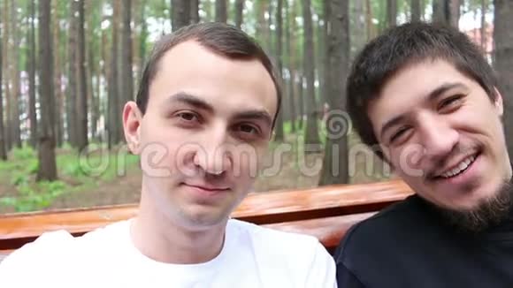 两个英俊的男人坐在长凳上对着镜头微笑正常动作视频的预览图