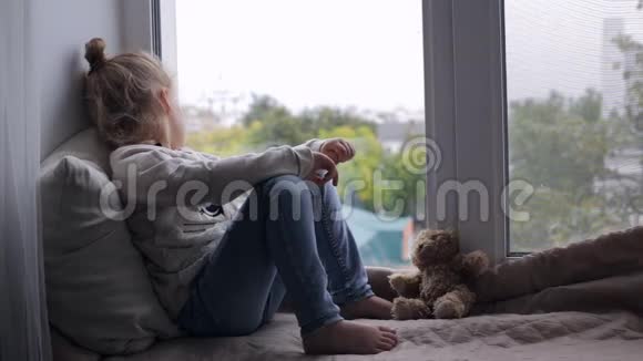伤心可爱的女孩坐在窗台上视频的预览图