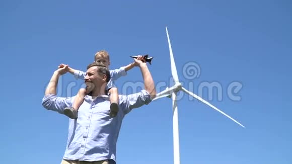 在风力发电机的背景下父亲把儿子抱在肩上视频的预览图