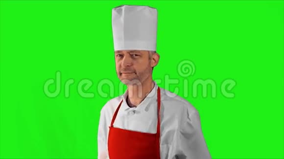 英俊的成年厨师转过身来交叉双臂在绿色的背景上点了点头视频的预览图